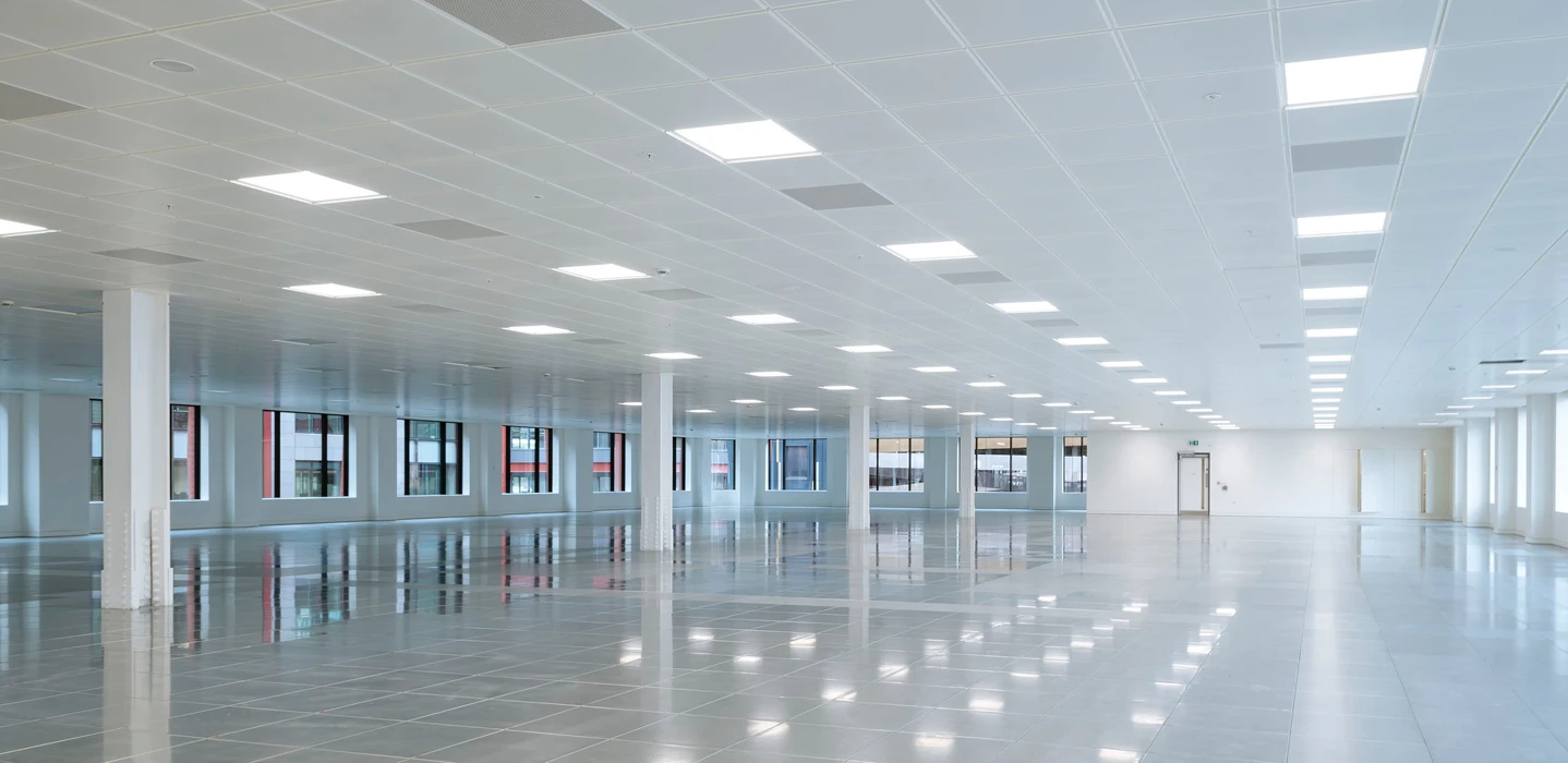 A large well lit white room with windows along one of the walls