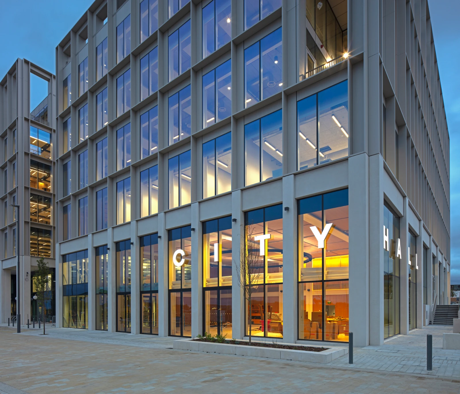 A modern office building lit up from the insight at dusk